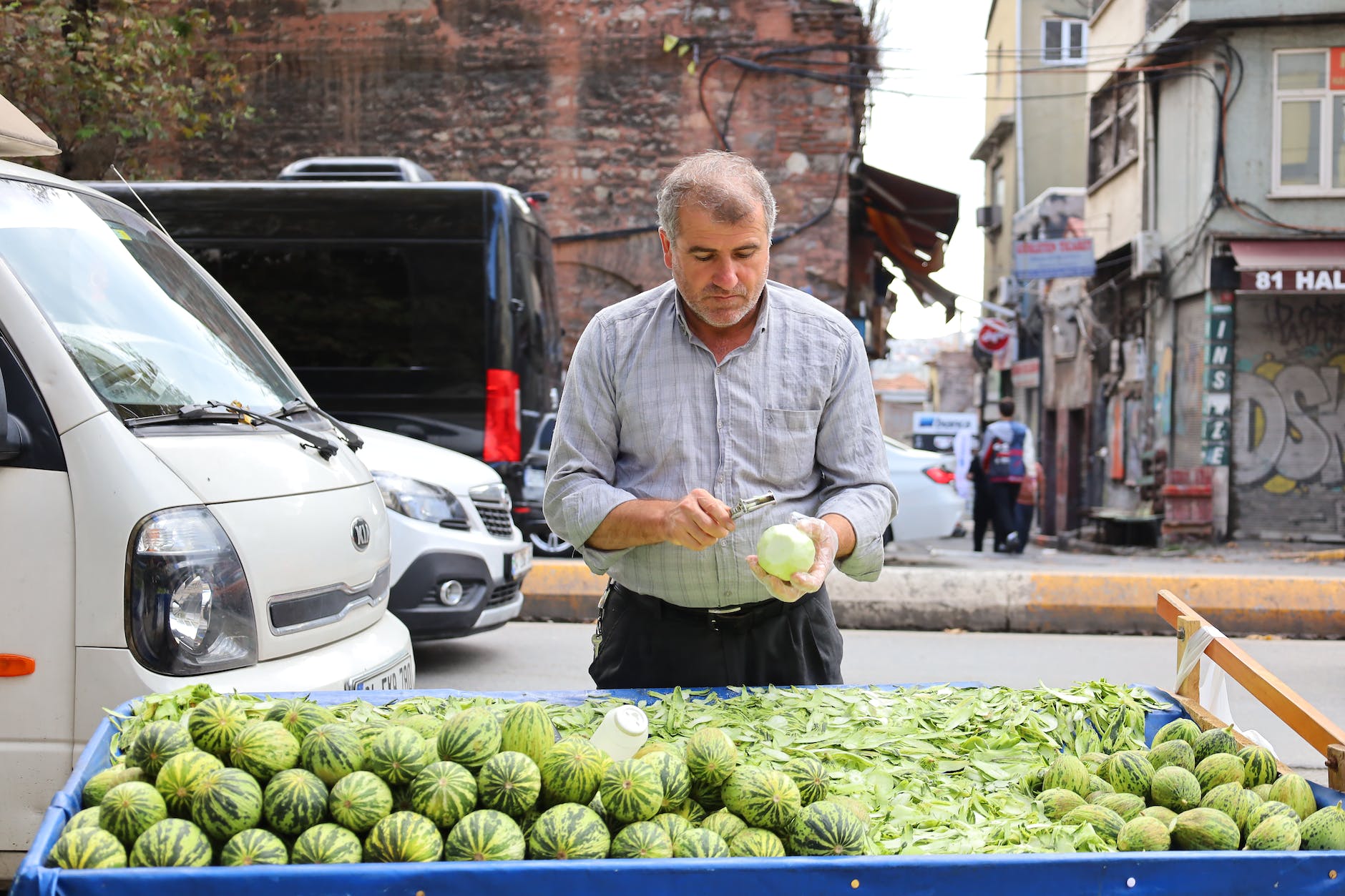 man in shirt peeling fruit at market