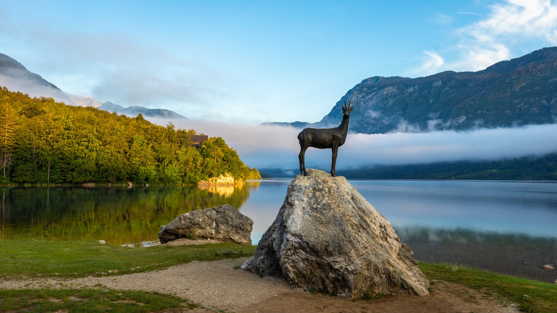 early morning view at lake bohinj in bohinj with the statue of goldhorn zlatorog on the rock