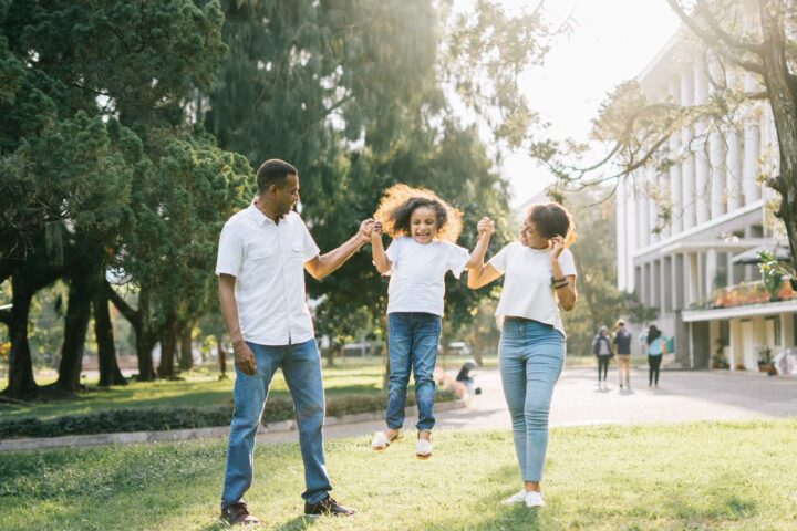 a man and a woman assisting a girl while jumping