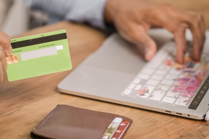 person holding green card while using silver laptop