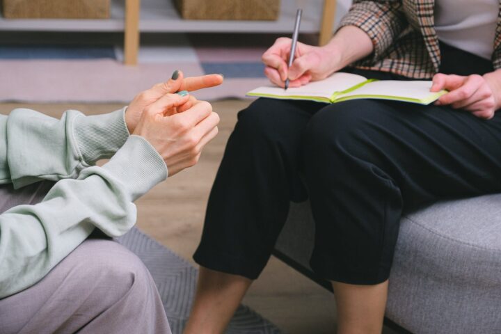 anonymous female therapist and client sitting in armchairs during session in modern office