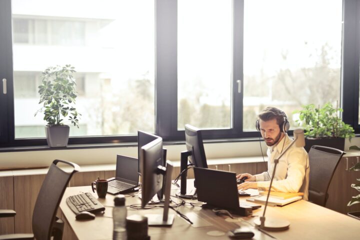 man with headphones facing computer monitor