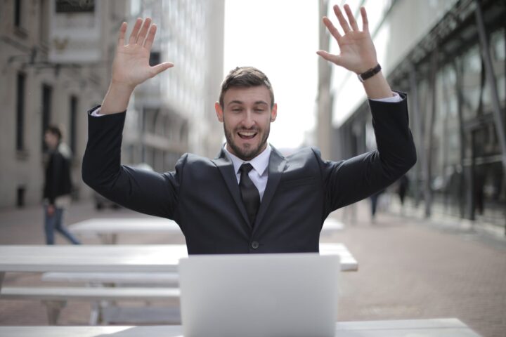 man in black suit raising both hands