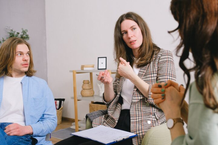 pensive psychologist talking with couple in light room