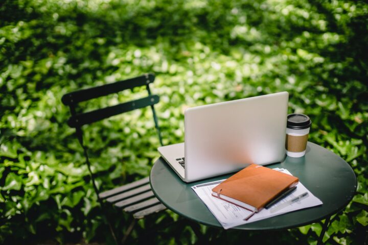 cozy table with laptop and notebook in park