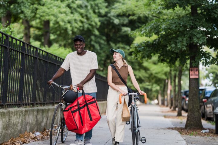 colleagues from delivery services wheeling bikes after job