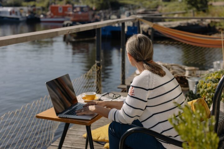 woman in white and black striped sweater sitting on chair using laptop computer