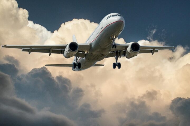 white and red plane beside clouds low angle photography