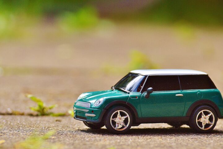 green scale model car on brown pavement