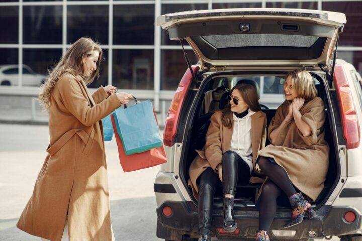 young woman demonstrating shopping bags to friends